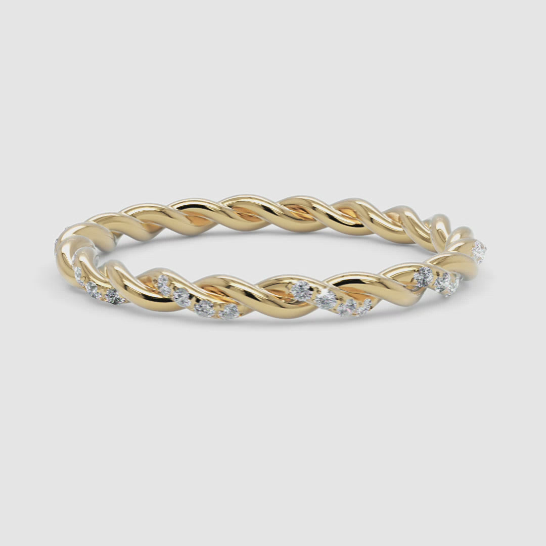 A 360-degree video of a 14k yellow gold twisted diamond eternity band, smoothly rotating to reveal its delicate twisted gold design and sparkling row of round brilliant diamonds from every angle.