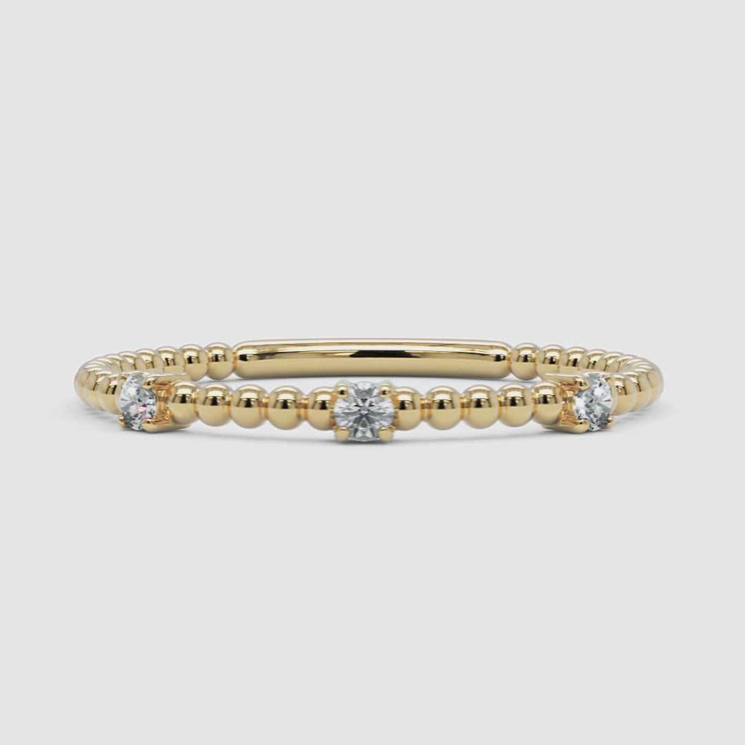A 360-degree video of a 14k yellow gold diamond beaded ring, smoothly rotating to display its delicate gold bead design and three prong-set round diamonds from every angle. A refined stacking piece with a subtle shimmer.
