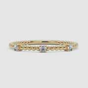 A 360-degree video of a 14k yellow gold diamond beaded ring, smoothly rotating to display its delicate gold bead design and three prong-set round diamonds from every angle. A refined stacking piece with a subtle shimmer.