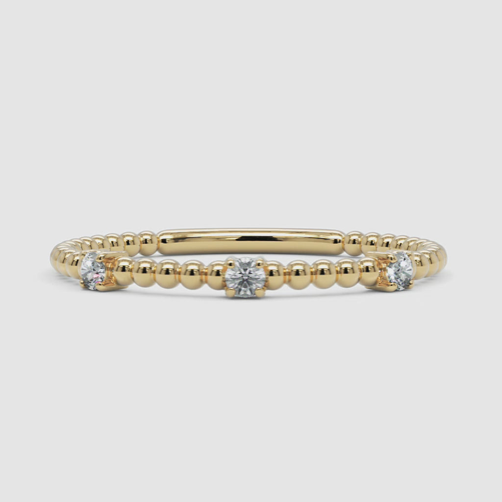 A 360-degree video of a 14k yellow gold diamond beaded ring, smoothly rotating to display its delicate gold bead design and three prong-set round diamonds from every angle. A refined stacking piece with a subtle shimmer.