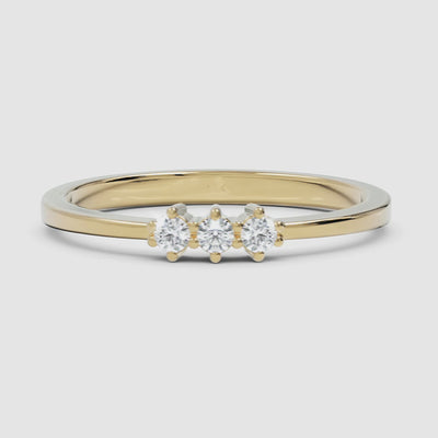 A 360-degree video of a 14k yellow gold three-stone diamond ring, smoothly rotating to reveal its polished gold band and prong-set round diamonds from every angle.