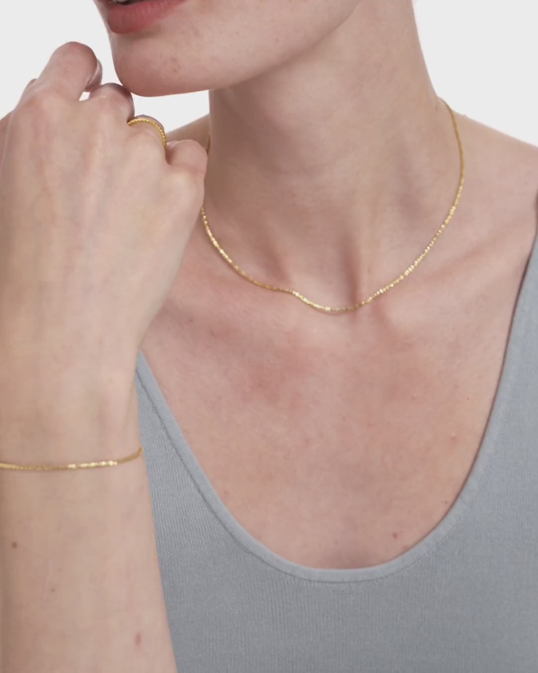 Video of a woman wearing the Lumière Sparkle Chain Necklace in 14k yellow gold, the diamond cut links flickering as she moves. ENEA Studio