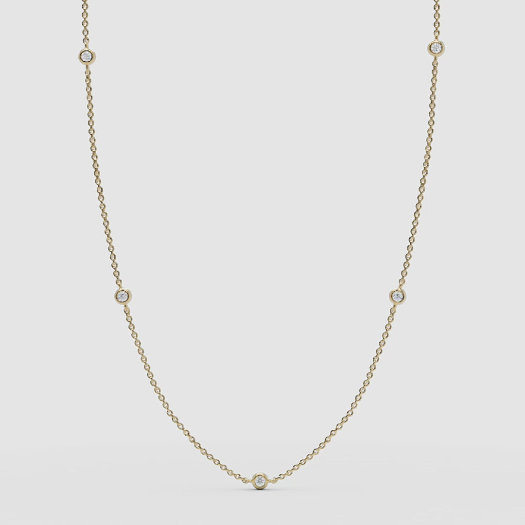 Full view of the 14k yellow gold station necklace featuring delicate bezel-set diamonds.