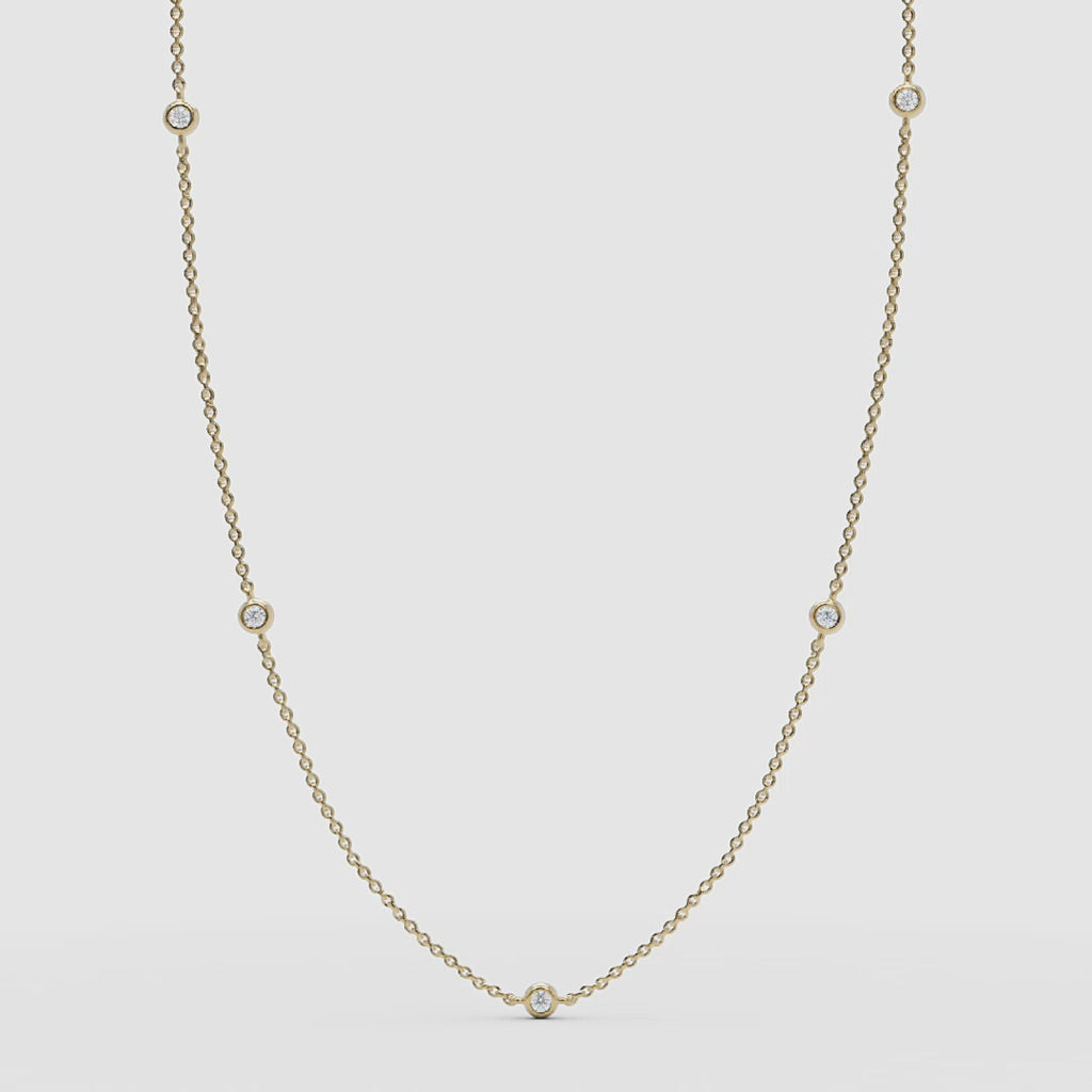 Full view of the 14k yellow gold station necklace featuring delicate bezel-set diamonds.