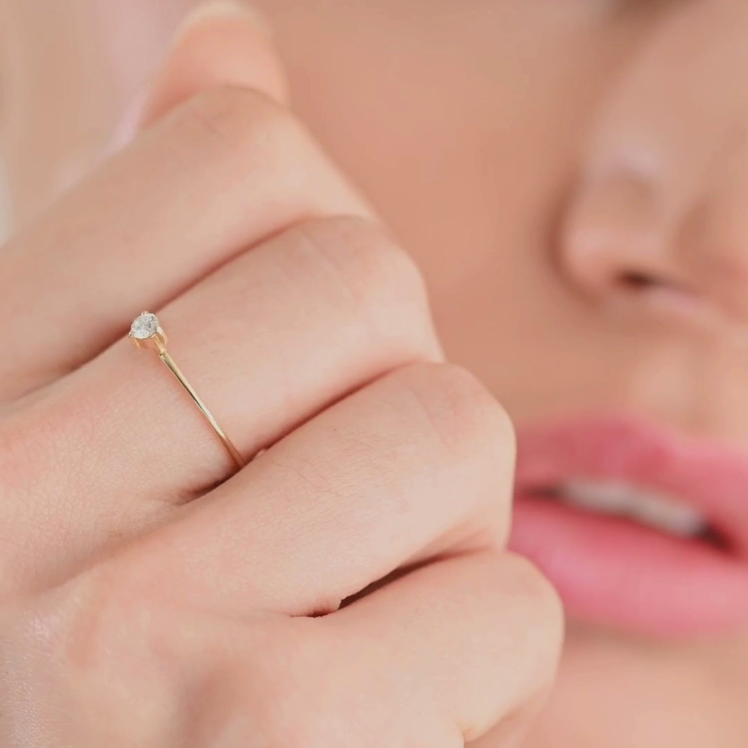A close-up video of a woman wearing a 14k yellow gold solitaire diamond ring. The camera captures the delicate sparkle of the round brilliant-cut diamond as she moves her hand, showcasing the ring’s fine band and timeless elegance.