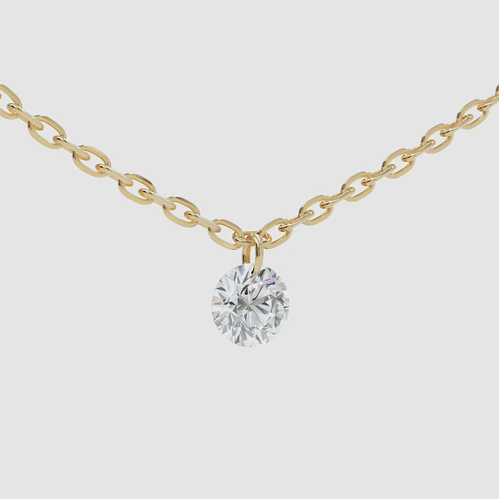 Close-up video of a 14k gold chain necklace featuring a round brilliant-cut diamond solitaire charm, gently swaying left to right.
