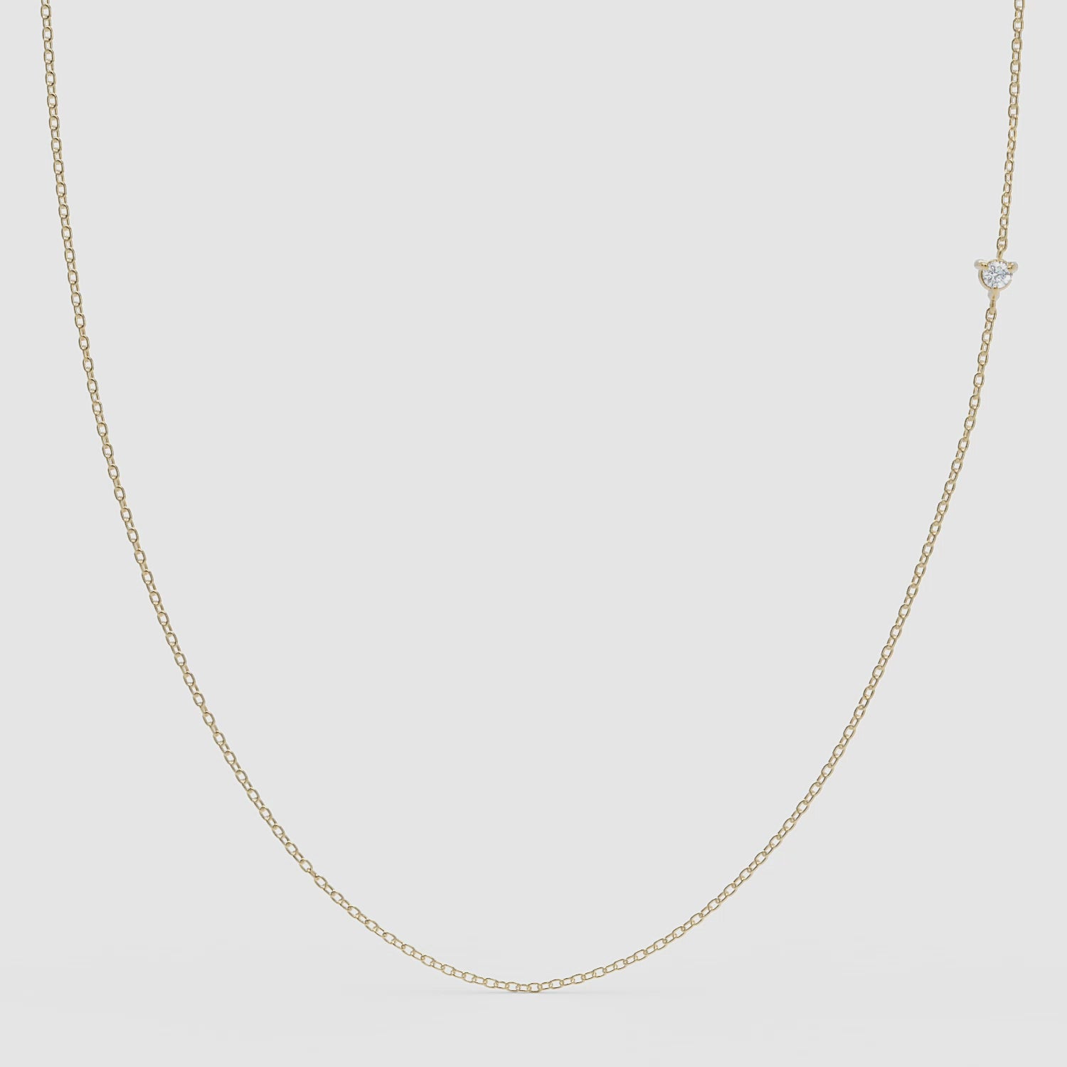 360° view of a minimalist 14k gold chain necklace featuring a small round diamond set off-center, designed to be worn with either side facing forward.
