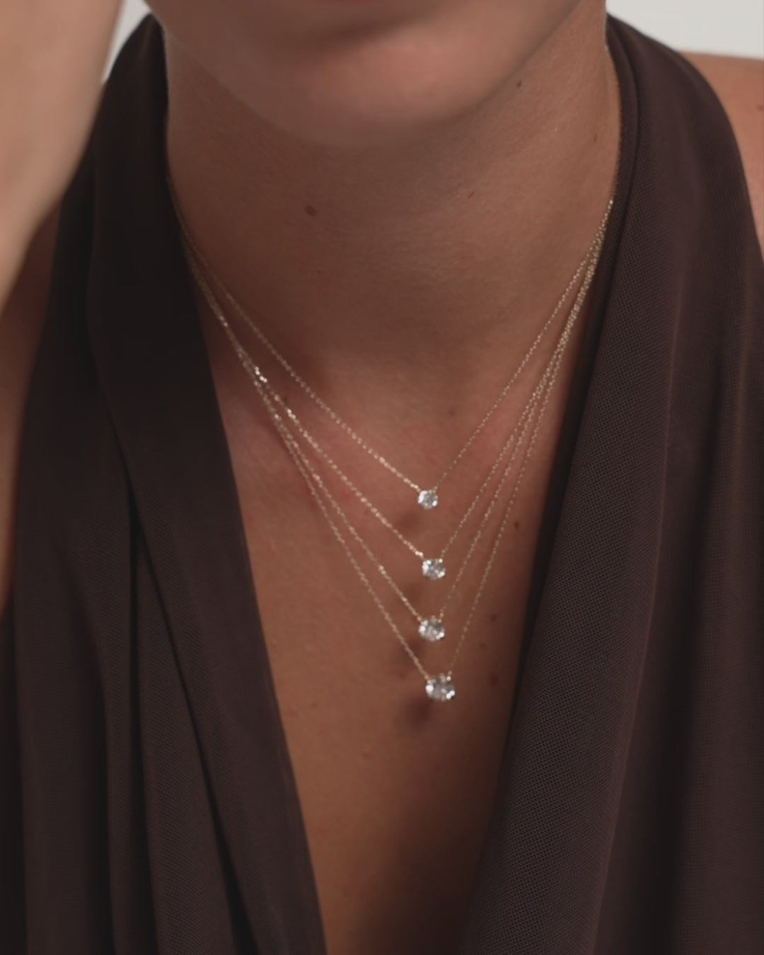 Video of a woman wearing the 14k gold eclat grand diamond solitaire necklace by Enea layered in four diamond sizes on her neck
