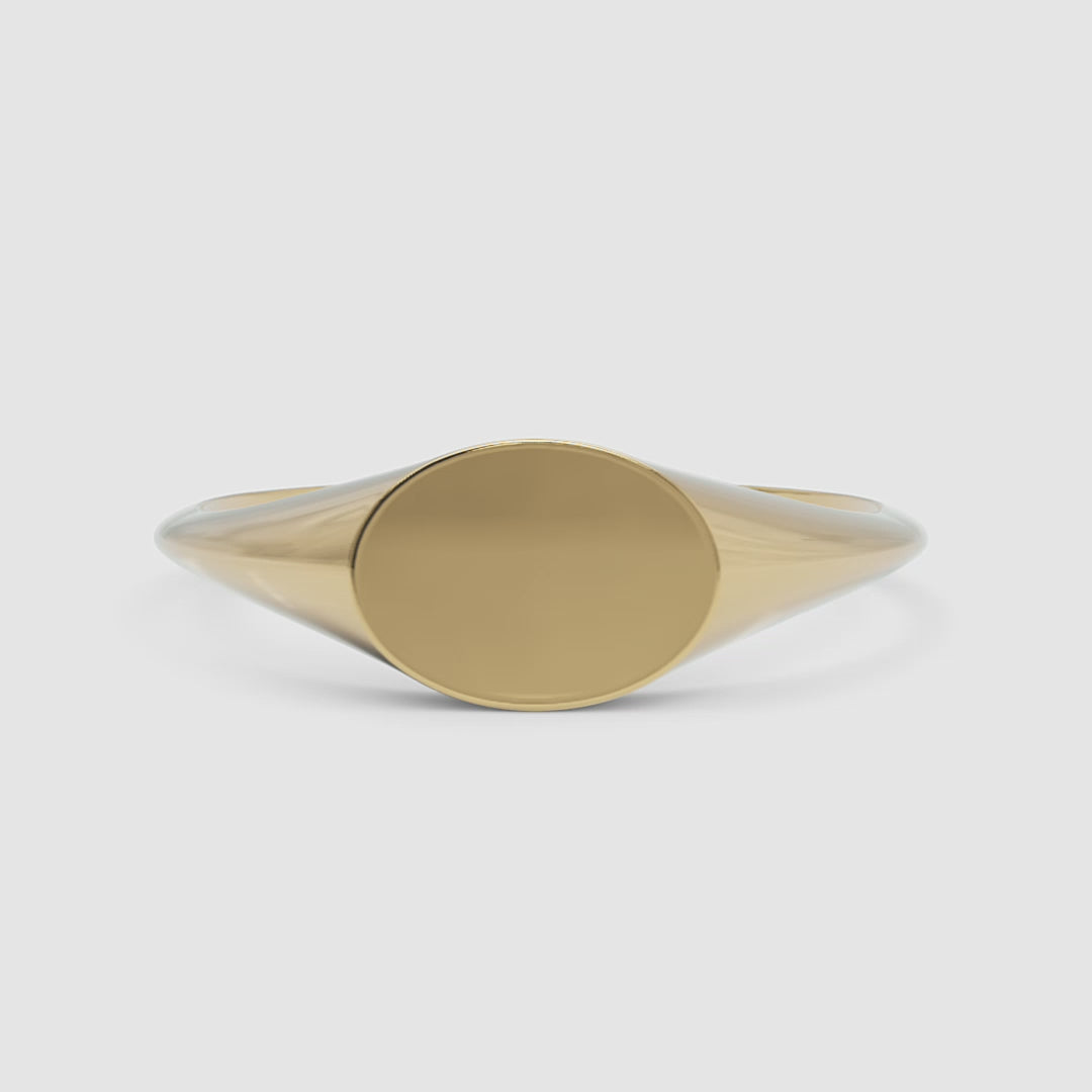 A 360-degree video of a 14k yellow gold oval signet ring, smoothly rotating to reveal its polished gold surface and classic oval silhouette from every angle.