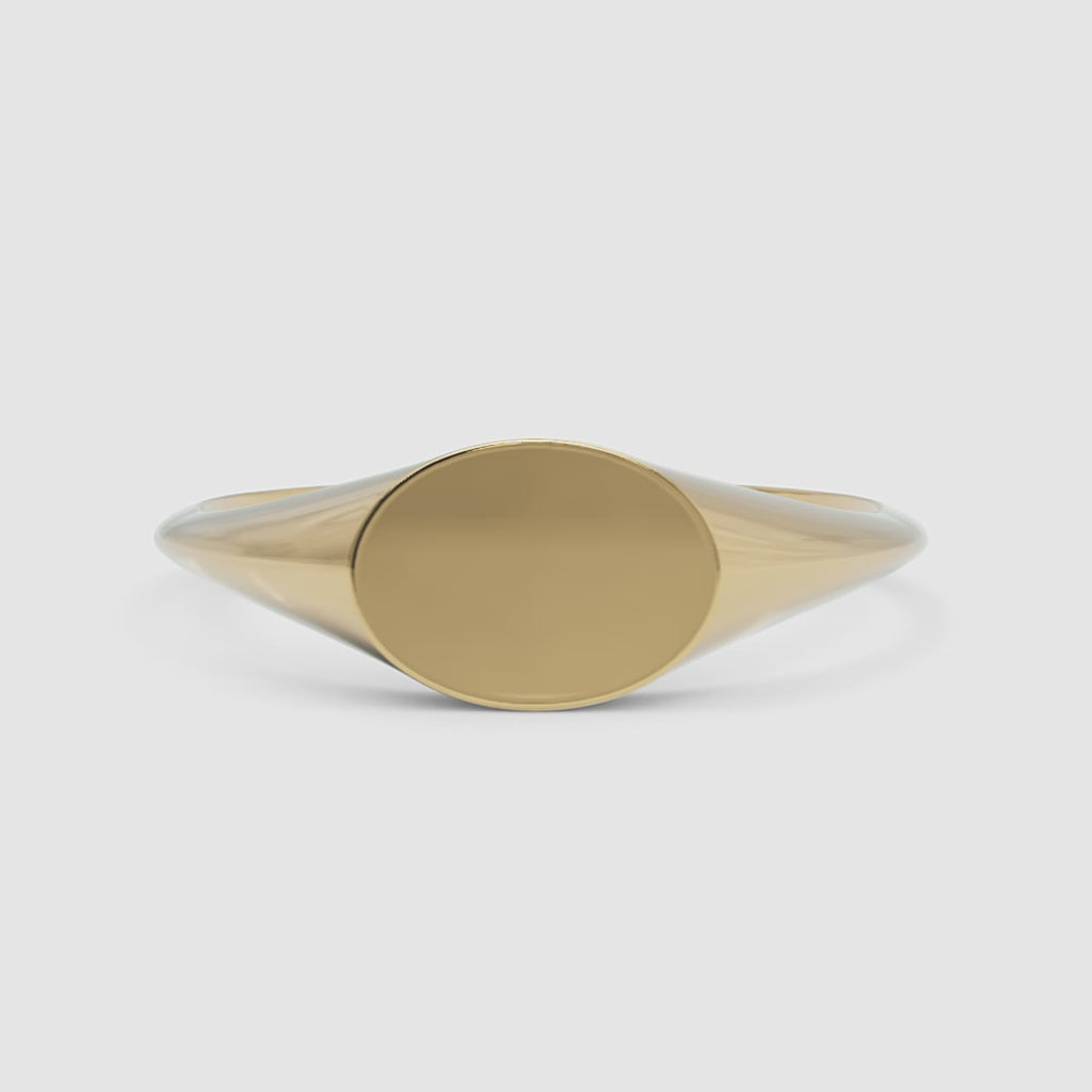 A 360-degree video of a 14k yellow gold oval signet ring, smoothly rotating to reveal its polished gold surface and classic oval silhouette from every angle.