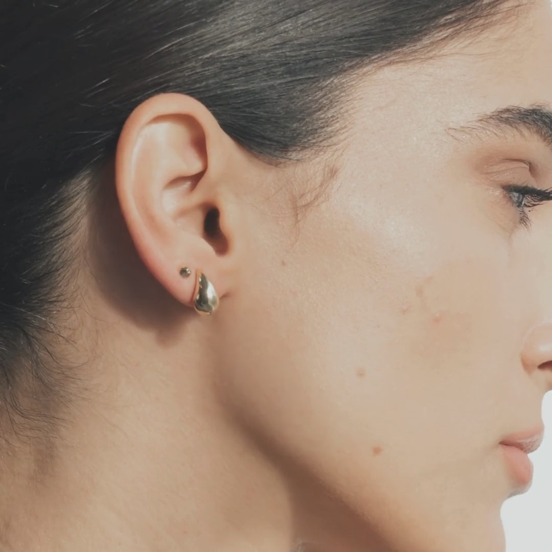 Model wearing the puffy teardrop stud earrings, gently moving her head to highlight their shape and shine under soft, natural light.