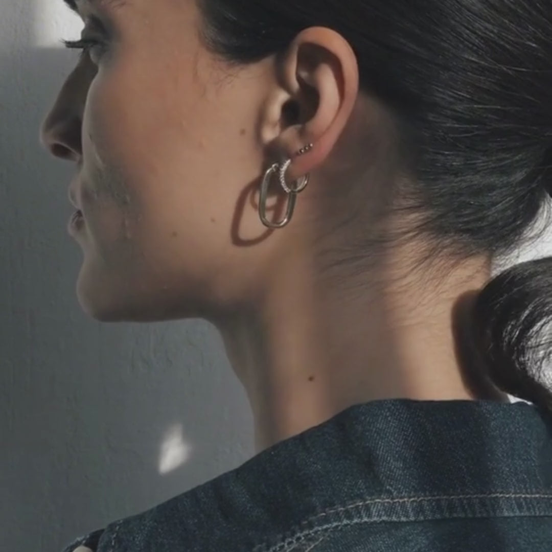 Video of a model turning her head slowly while showcasing 14k gold earrings in soft natural light.
