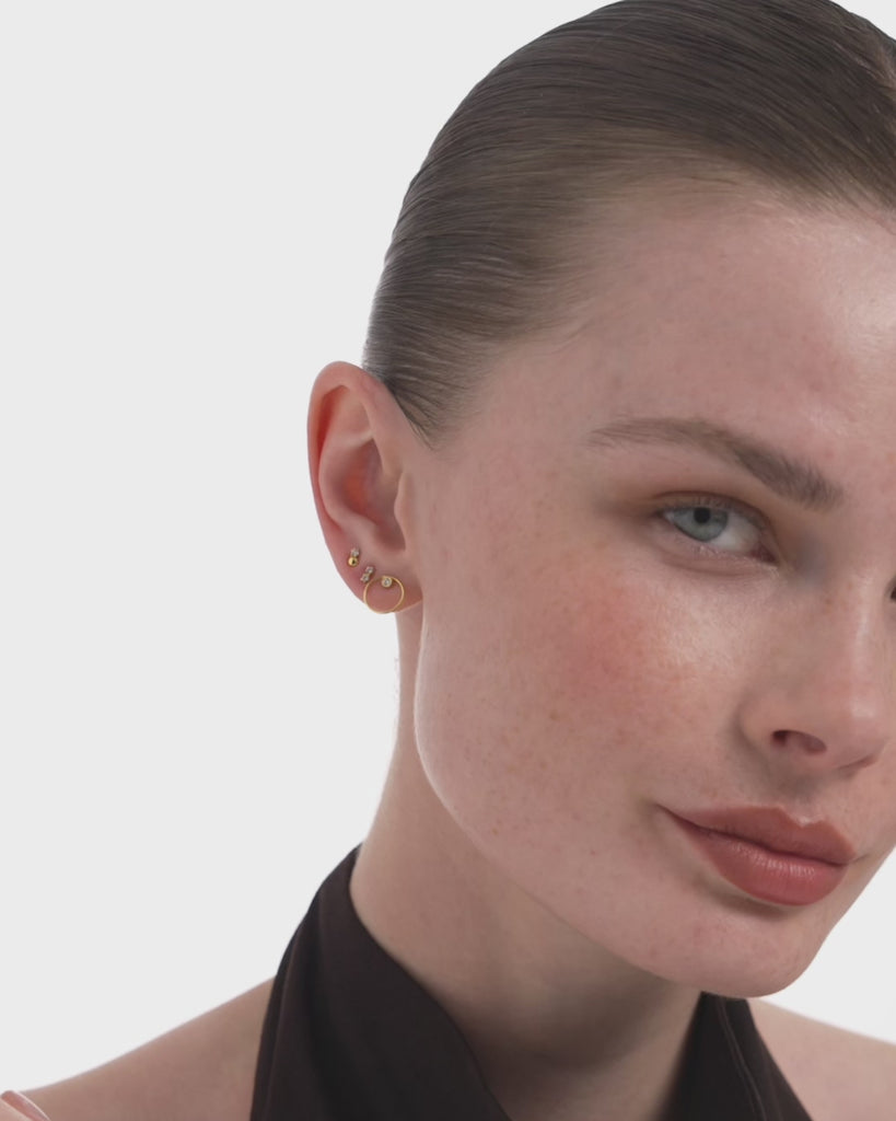 Video of a woman wearing the Dyo Diamond Bead Studs in 14k yellow gold, a lab grown diamond beside a polished gold bead, catching light as she moves. ENEA Studio