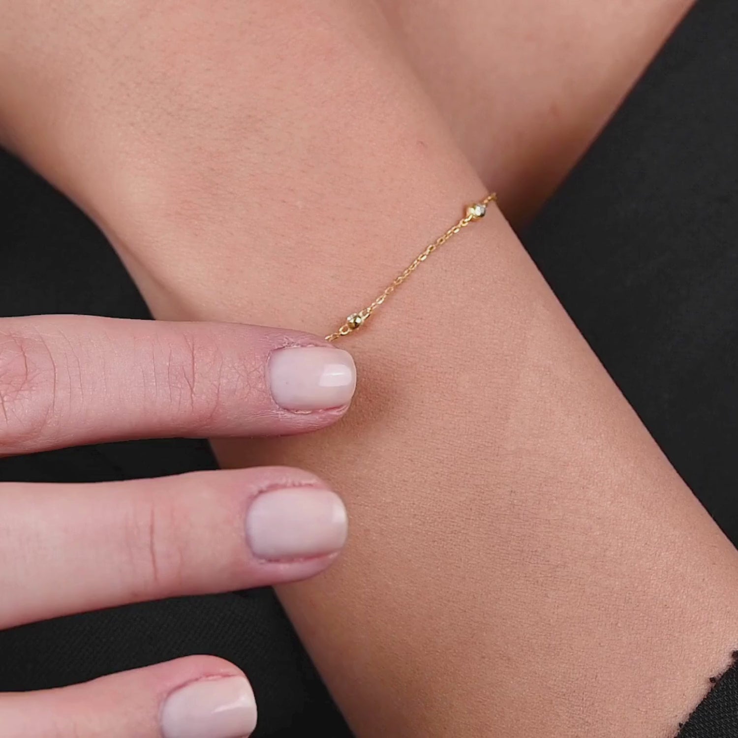 Detailed shot of the bracelet clasp and diamonds as a model adjusts the piece, showing fine craftsmanship.

