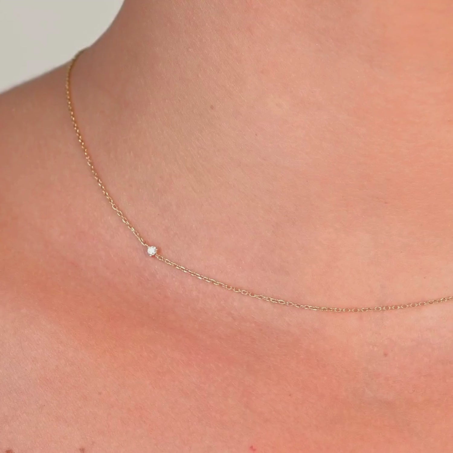 Video of a Close-up side angle of the diamond choker on a model's neck, highlighting the solitaire diamond on the thin gold chain.

