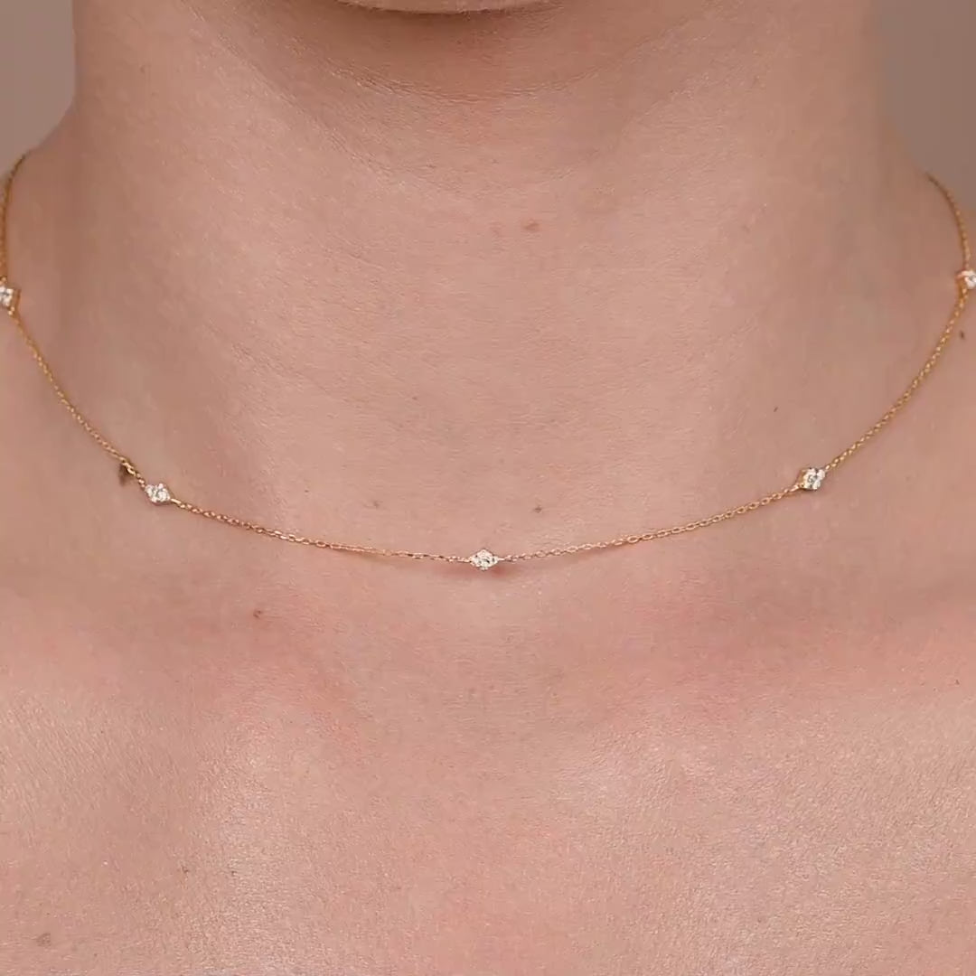 Close-up of yellow gold necklace with multiple diamonds spaced evenly, worn as a minimalist layering piece.
