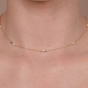 Close-up of yellow gold necklace with multiple diamonds spaced evenly, worn as a minimalist layering piece.