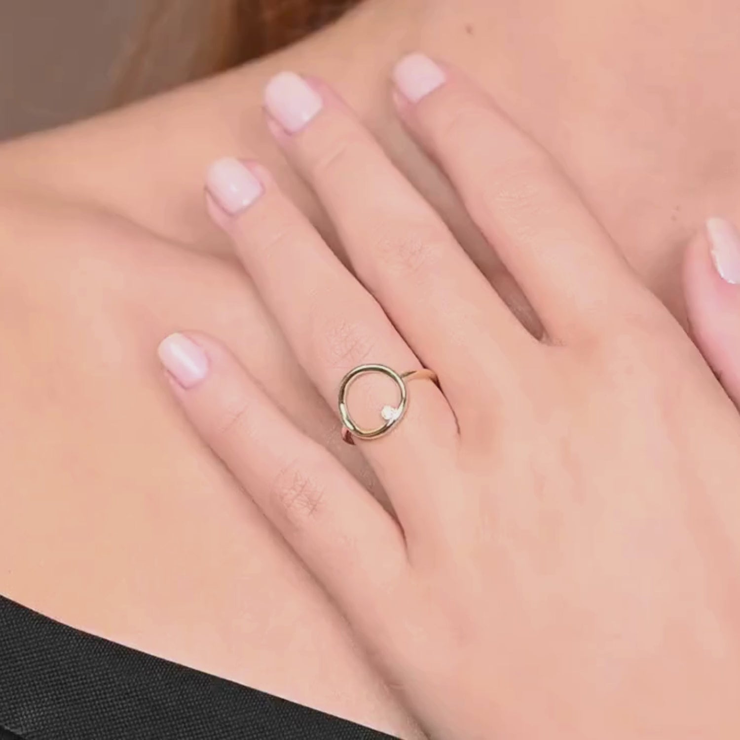 A close-up video of a woman wearing a 14k yellow gold open circle diamond ring, moving her hand naturally to showcase its sculptural elegance and subtle sparkle.