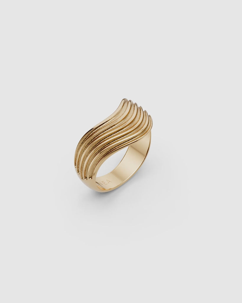 Video giving a 360 view of the Kion III Ribbed Wave Ring in yellow gold on a white surface