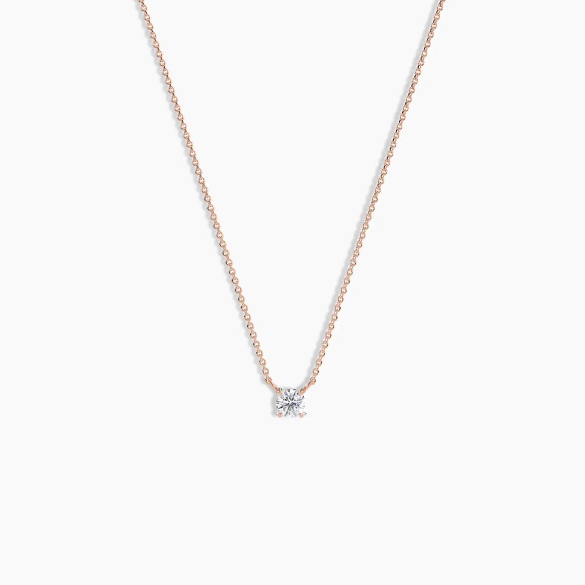 Delicate rose gold necklace featuring a single round-cut solitaire diamond pendant, displayed on a clean white background.
